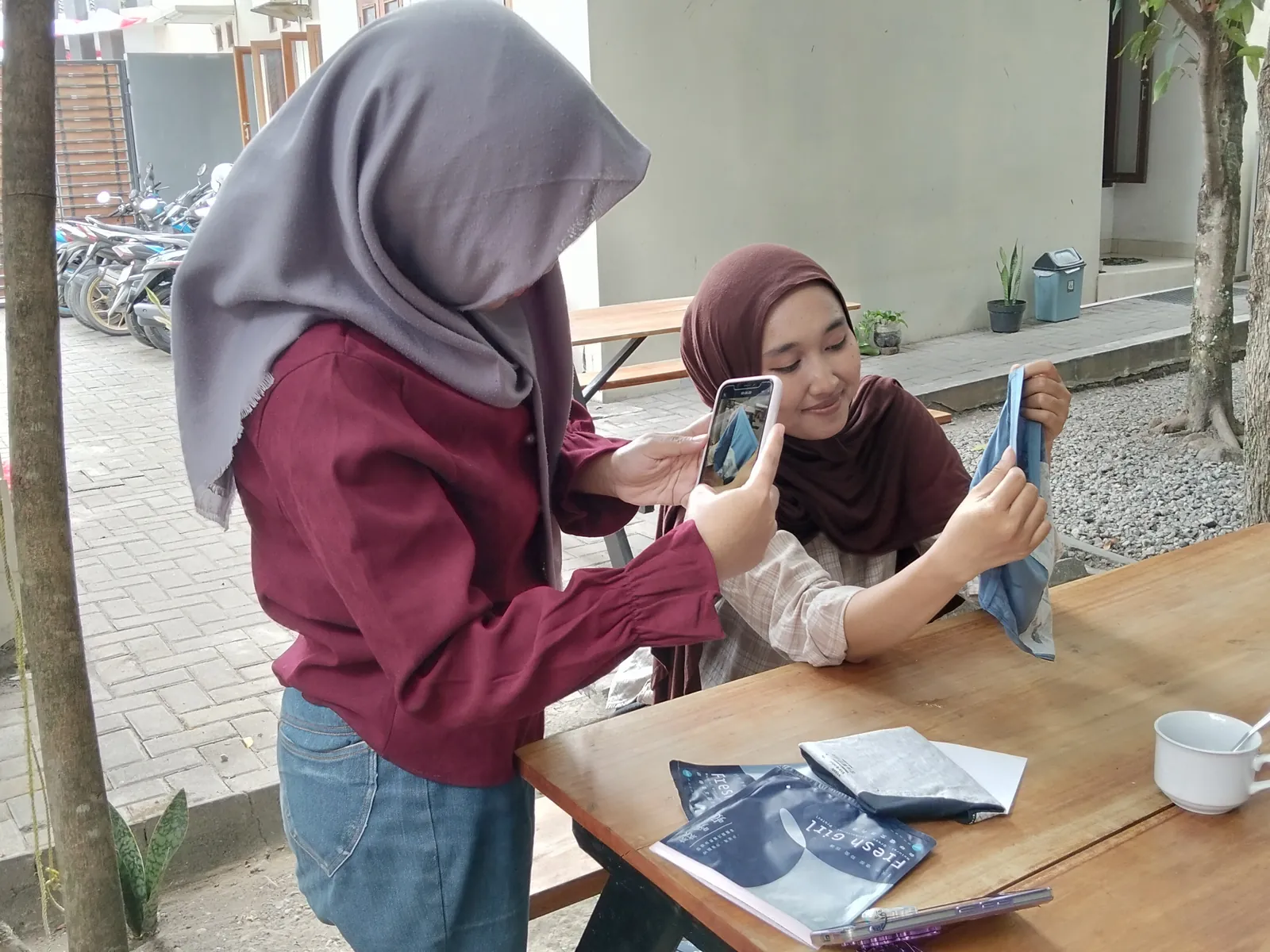 Dua peserta memotret produk dengan ponsel di area terbuka kantor